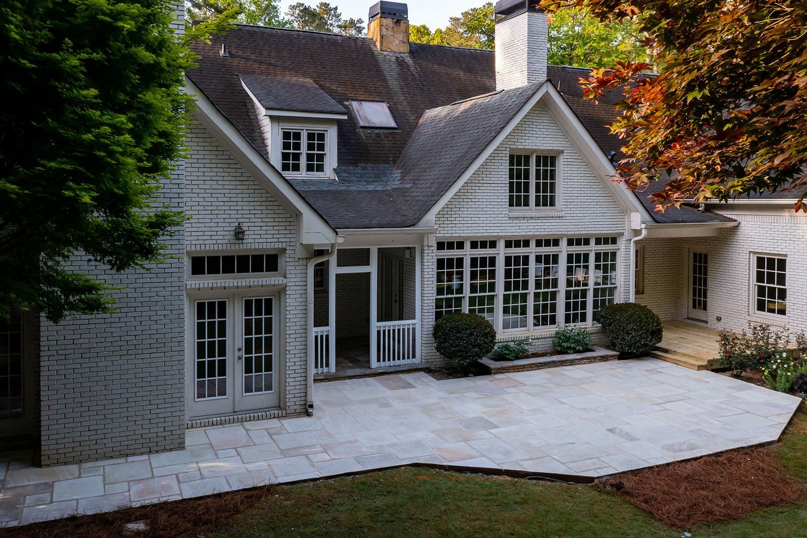 A white-brick Atlanta home with a new cut-sandstone terrace spanning its rear elevation
